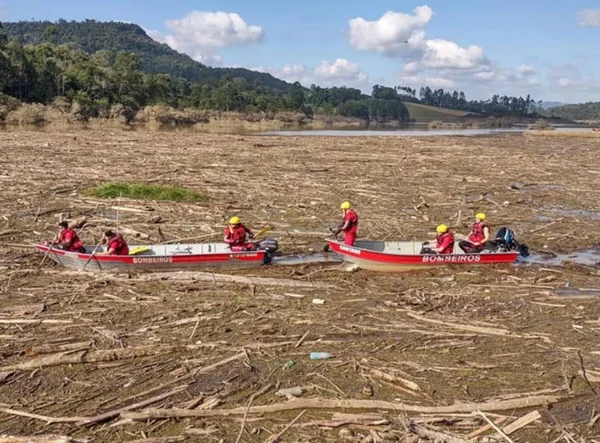 foto colorida de barco de bombeiros em barragem com entulho