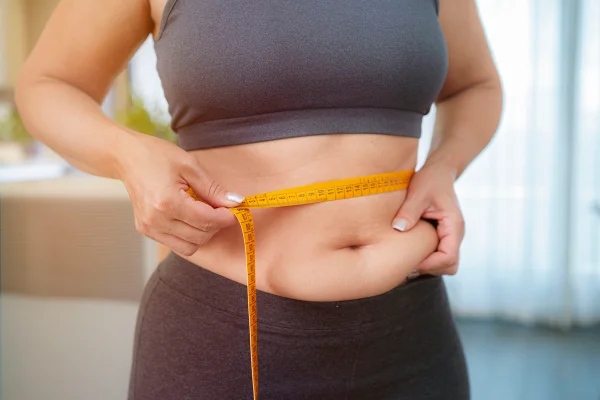Mulher medindo a barriga com fita métrica - Gordura localizada: como o organismo escolhe o que queimar - Metrópoles