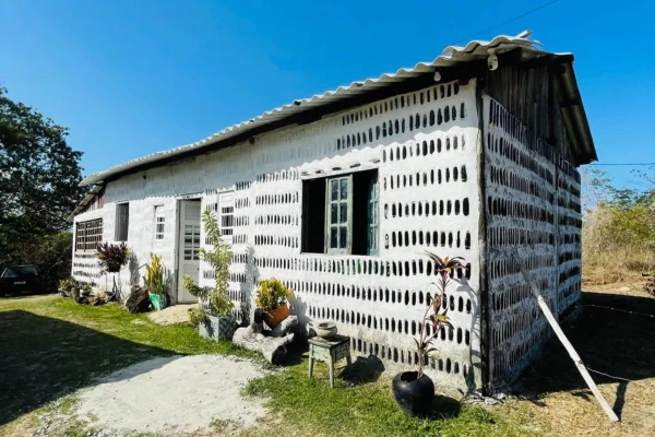 foto colorida de foto de casa construída com 8 mil garrafas de vidro