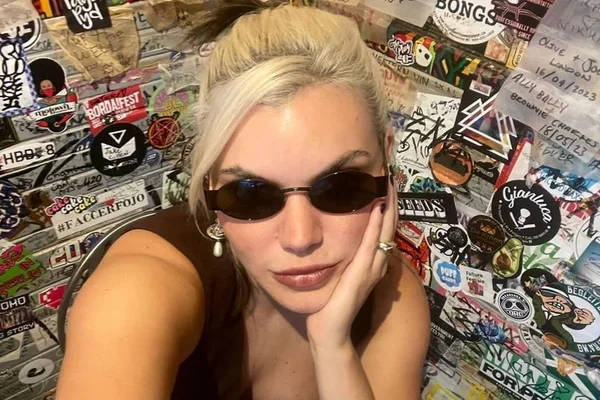 Foto colorida da cantora Duda Beat sentada com óculos escuros - Metrópoles