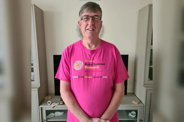 Foto Darren Harris, britânico de 59 anos, que descobriu um tumor no cerebral. Ele veste camisa rosa e esta com os braços na frente do corpo. Metrópoles
