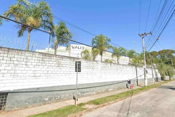Fotografia colorida de prédio ao fundo com muro branco
