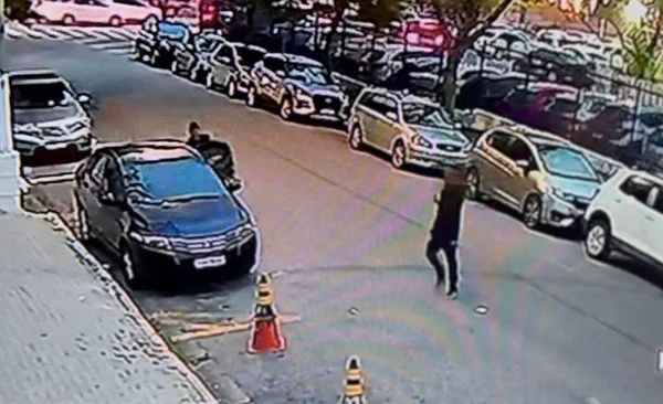 Em imagem colorida homens se aproximam de carro na rua - Metrópoles