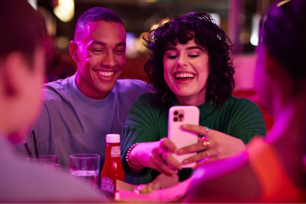 casal interacial mexendo no celular em um lugar cheio