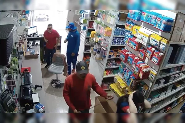 Imagem colorida de três bandidos rendendo uma funcionária em uma loja de informática