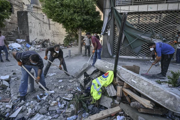 Libaneses retiram entulhos na área depois que aviões de guerra israelenses atingiram um prédio na área de Bachoura, em Beirute, Líbano Metropoles