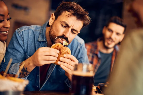 Imagem colorida de homem comendo alimento ultraprocessado - Metrópoles