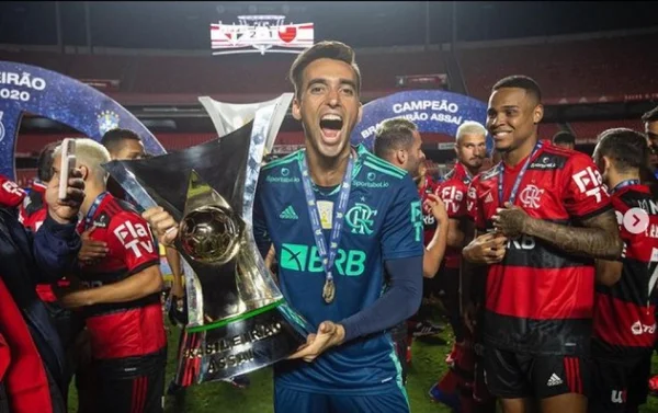 Goleiro Cézar, ex-Flamengo. Na foto, ele aparece no gramado do campo com ataça de campeão brasileiro de 2020.