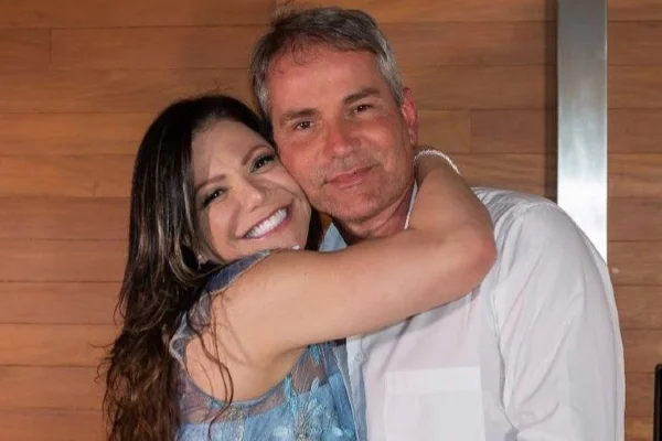 Fotografia colorida de Simone e Márcio abraçados e sorrindo enquanto postam para foto