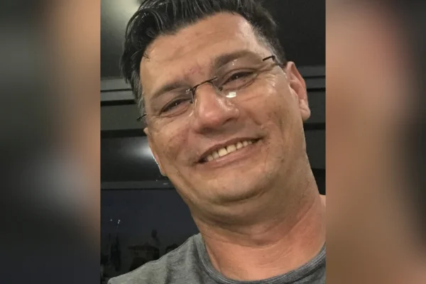 Imagem colorida de homem de óculos sorrindo. Metrópoles
