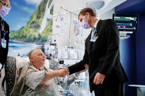 Foto mostra homem branco, de meia idade, com uma traqueostomia. Ele é Marty Kedian, homem que passou por transplante de laringe, uma rara operação