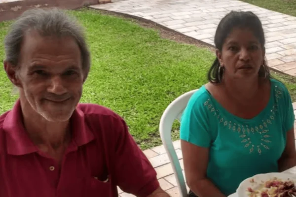 Imagem colorida de um homem vestido de camisa vermelha sentado ao lado de uma mulher vestida de verde - Metrópoles
