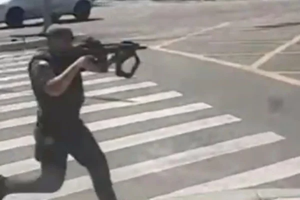 Imagem colorida de policial apontando arma. Metrópoles