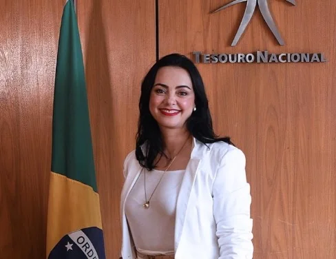 Viviane Varga, nomeada secretária adjunta do Tesouro, é servidora de carreira da pasta. Na imagem ela sorri em frente à bandeira do Brasil - Metrópoles