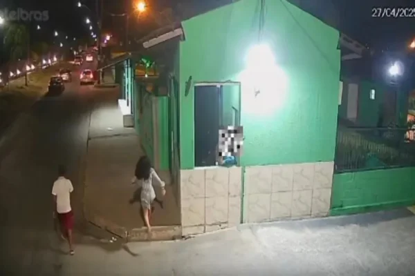 Imagem colorida da fachada de uma casa verde com pessoas ao redor - Metrópoles