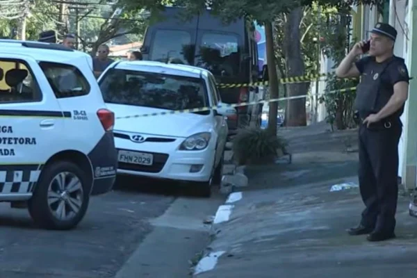 Imagem colorida mostrando viatura da polícia, carro branco e um GCM em pé após tiroteio - Metrópoles