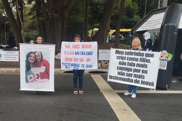 Imagem colorida de mulheres segurando faixas de protesto contra as Testemunhas de Jeová. Metrópoles