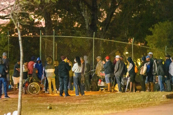 Foto colorida de pessoas em fila de abrigo emergencial do DF