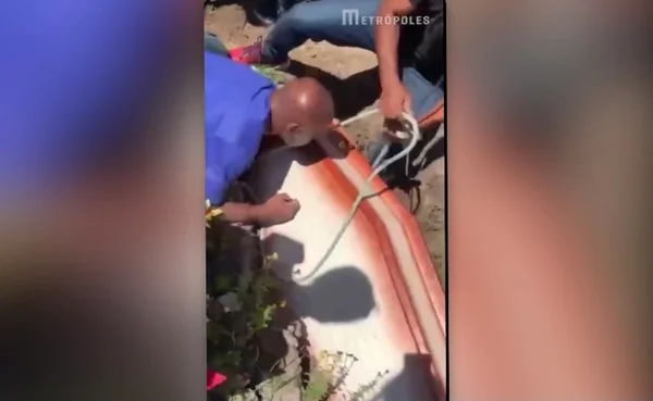 Homens tentam amarrar caixão que se abriu com uma corda