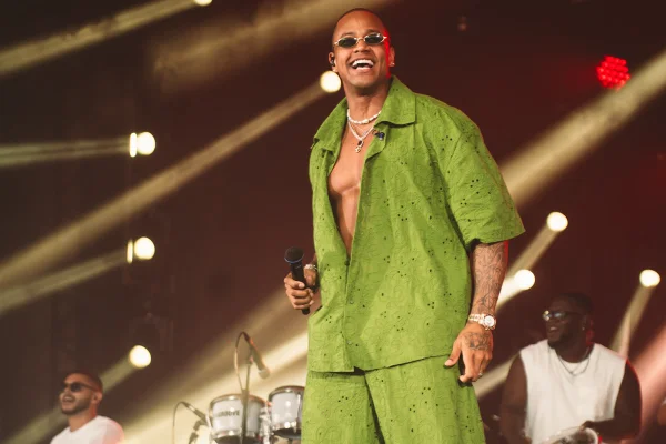 Foto de Léo Santana sorridente no palco com um look verde - Metrópoles
