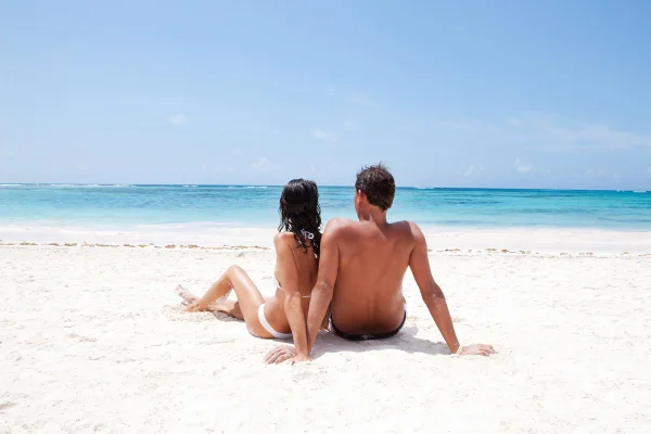 Casal relaxando na praia. Protetor solar, sol forte, câncer de pele