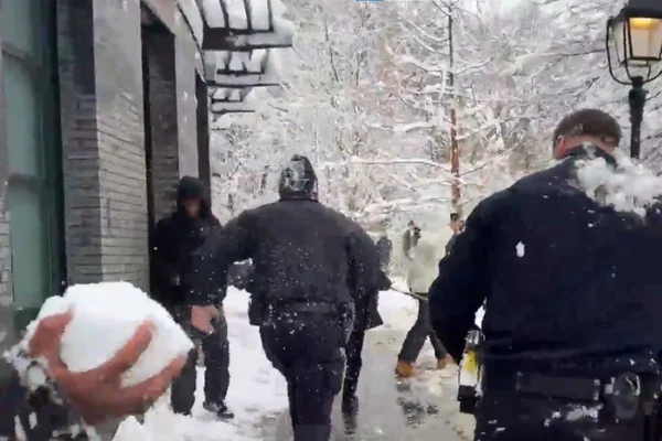 Foto colorida de policias de NY sendo atingidos por bolas de neve - Metrópoles
