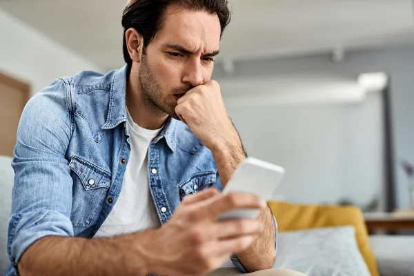 Imagem colorida de um homem lendo conteúdo no celular - Metrópoles