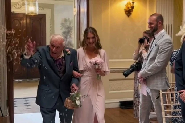 Idoso e madrinha entrando em cerimônia de casamento