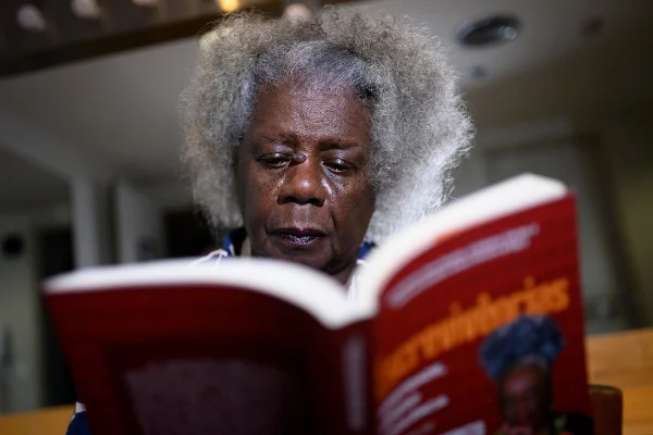 Imagem colorida da escritora Conceição Evaristo lendo um livro - Metrópoles