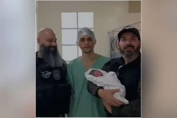 Imagem colorida mostra os policiais civis Daniel Presutti e Felipe Viotto, do Grupo Armado de Repressão a Roubos e Assaltos (Garra), com o bebê - metrópoles
