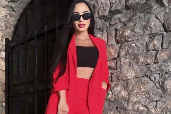 Pablinny Faleiro Pedersoli posa de look preto e vermelho, óculos escuros e cabelos soltos - Metrópoles