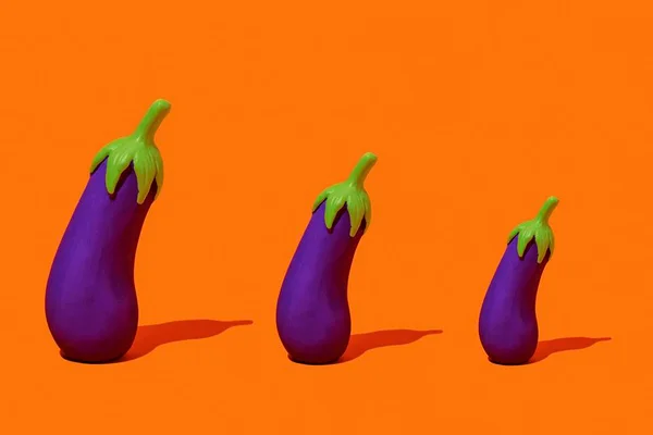 Três berinjelas uma ao lado da outra em um fundo laranja - Metrópoles
