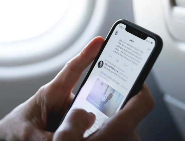 Pessoa mexendo no app Twitter no celular em avião - Metrópoles