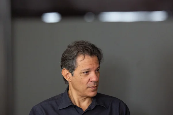 O pré-candidato ao governo de São Paulo, Fernando Haddad (PT), concede entrevista ao Metrópoles. Ele gesticula, sentado sob fundo cinza - Metrópoles