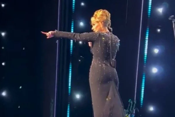 Foto colorida de Adele no Palco apontando para frente - Metrópoles