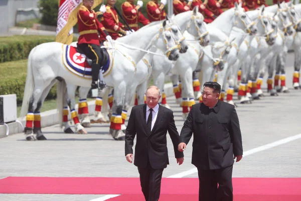 Imagem colorida mostra Putin e Kim Jong-un caminhando lado a lado - Metrópoles