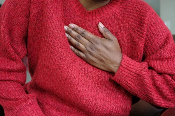 Foto colorida de mulher com a mão no peito - Soluço: saiba causas, quando se preocupar e como interromper incômodo - Metrópoles
