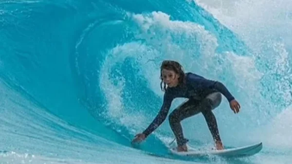 Imagem colorida de Khai Cowley surfando - Metrópoles
