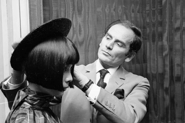 O estilista francês Pierre Cardin ajeita o chapeu na cabeça de uma modelo em sua loja recém aberta em Patris, em 1953 - Metrópoles
