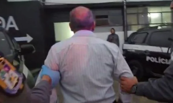 Imagem colorida de prisão de idoso acusado de abuso contra crianças em frente a escola