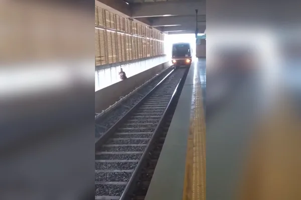 homem em cima de trilho com trem ao fundo