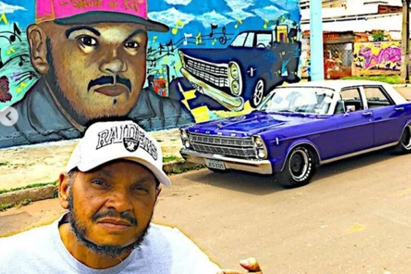 Dj Jamaika em frente a um carro azul - Metrópoles