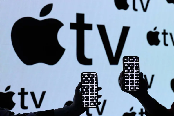 Painel led com o símbolo da apple tv e duas pessoas segurando um smartphone na frente - metrópoles