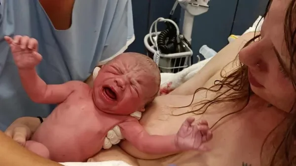 Foto de uma mulher segurando um bebê durante seu nascimento após ter dado à luz