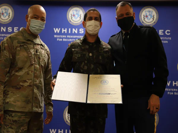 Foto de três militares, um deles, ao centro, Moacir Mendonça Lima, segura diploma