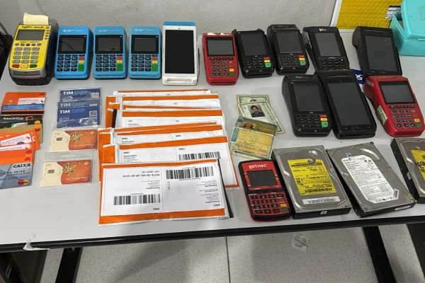 Imagem colorida de máquinas de cartão, documentos e objetos apreendidos em operação policial. Metrópoles