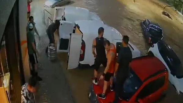 Comerciante usa barris de chope para impedir enchente de levar carros