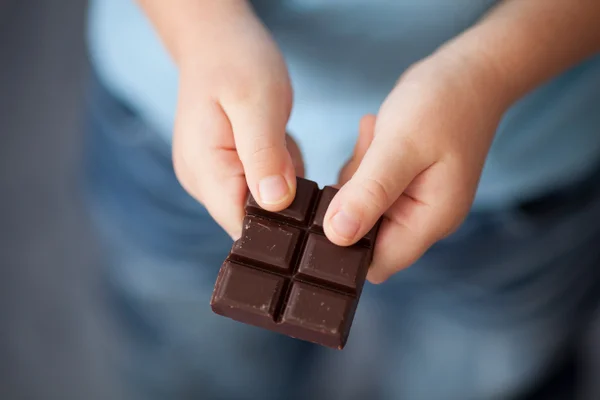 Foto colorida de criança segurando chocolate - Imagem ilustrativa - Metrópoles