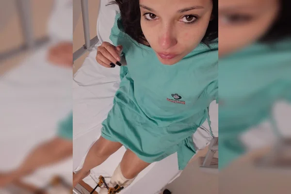 Mulher com roupa verde deitada em cama de hospital