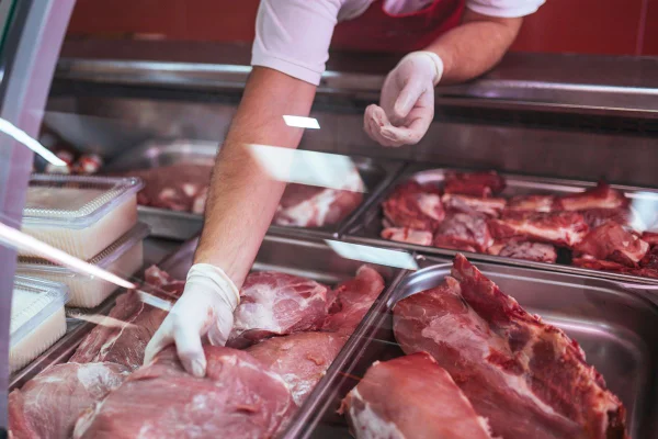 Foto mostra açougueiro manipulando carne vermelha